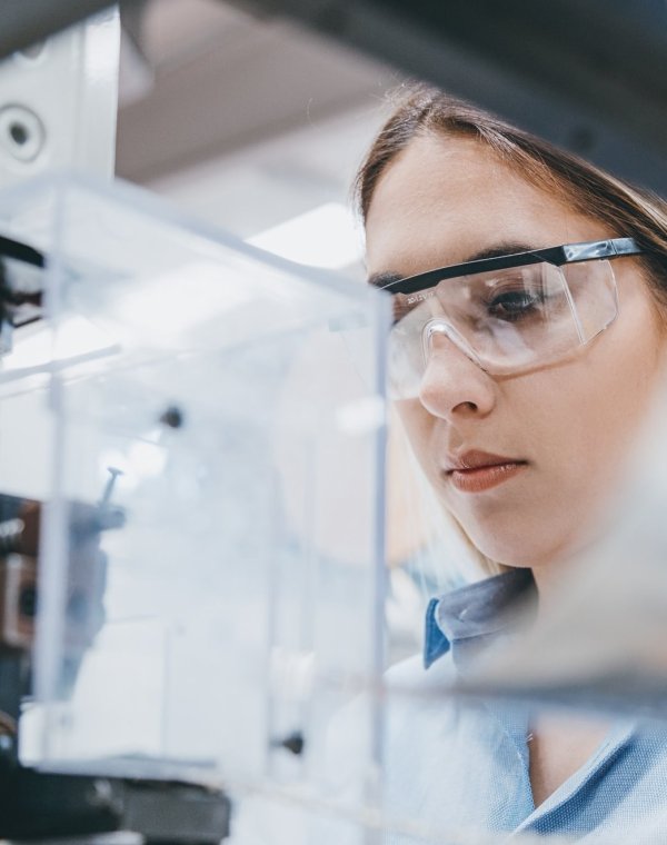 Professional young industrial factory woman employee working with machine parts putting, checking and testing industrial equipments cables in large Electric electronics wire and cable manufacturing plant factory warehouse