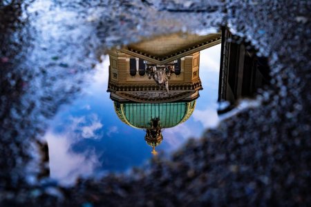 Das Bundeshaus in Bern spiegelt sich nach dem Regen in einer Pfütze.
