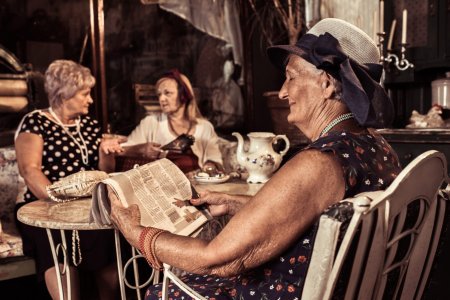 Elegant senior woman relaxing in a cafe with her friends while reading the latest news.