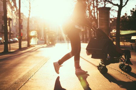 Photo of a modern mom having an easy walk and shopping with her baby in the strollers, outdoors in the city