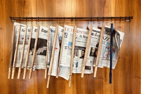 Sils Maria, Swizerland - August, 22 - 2022: International newspapers hanging at a wooden wall in a public library.