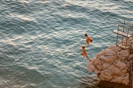 Teenagers having fun jumping from a cliff in to the sea
