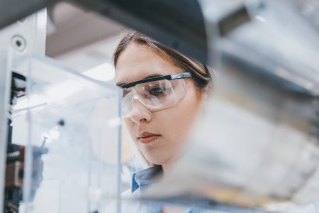 Professional young industrial factory woman employee working with machine parts putting, checking and testing industrial equipments cables in large Electric electronics wire and cable manufacturing plant factory warehouse