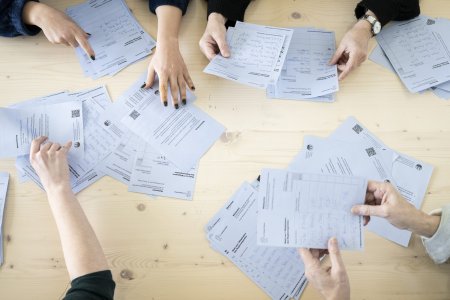 Freiwillige Mitarbeiter helfen beim Auslesen der Abstimmungsunterlagen zur Regierungs- und Kantonsratswahlen 2023 im Schulhaus Aemtler, aufgenommen am Sonntag, 12. Februar 2023, in Zuerich. (KEYSTONE/Ennio Leanza)