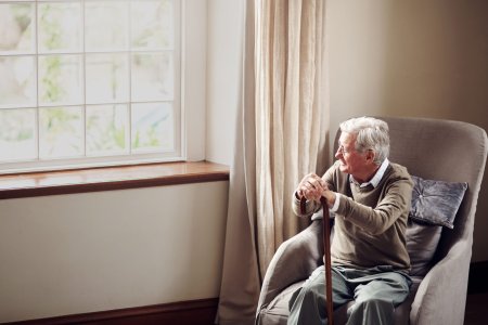 Shot of a senior man looking thoughtfully out of a window at home