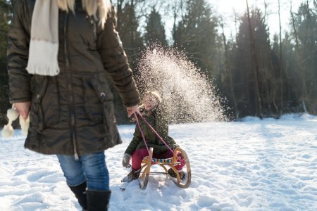 Mother pulls daughter on sledge