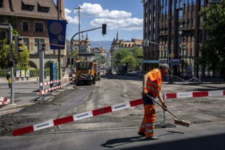 Un ouvrier balaie la route afin de pouvoir poser un nouveau revetement, un enrobe bitumineux de goudron phonoabsorbant, lors d?une conference de presse du syndicat UNIA afin de denoncer que sur les chantiers publics de genie civil, les conditions legales de protection des travailleurs ne sont pas reunies et mettent en danger leur sante, en periode de canicule. Une bonne soixantaine de chantiers a ete visitee par Unia et une trentaine de denonciations ont ete faites aupres des inspections du travail. Elles concernaient notamment l?absence de pauses regulieres, de mise a disposition d?eau et d?un lieu de pause au frais, ou encore la pratique de travaux lourds aux heures tres chaudes. (KEYSTONE/Martial Trezzini)
