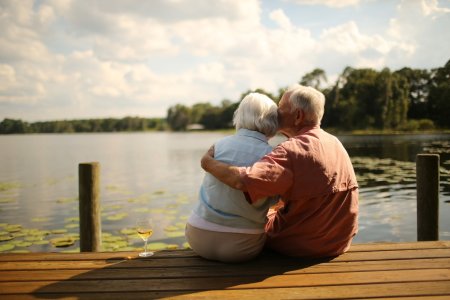 Rear view of romantic senior man kissing woman on wooden pier