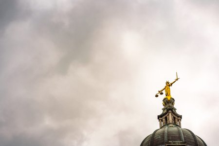 Storm clouds gathering above and around the statue of Lady Justice on the top of the main dome of the Royal Courts of Justice, known as Old Bailey after the street name in the City of London.