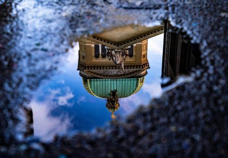 Das Bundeshaus in Bern spiegelt sich nach dem Regen in einer Pfütze.