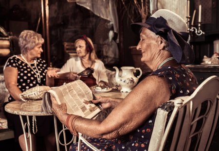 Elegant senior woman relaxing in a cafe with her friends while reading the latest news.