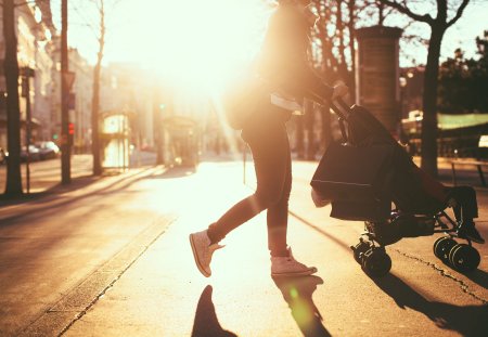 Photo of a modern mom having an easy walk and shopping with her baby in the strollers, outdoors in the city