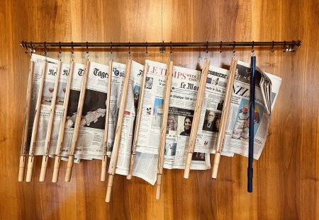 Sils Maria, Swizerland - August, 22 - 2022: International newspapers hanging at a wooden wall in a public library.