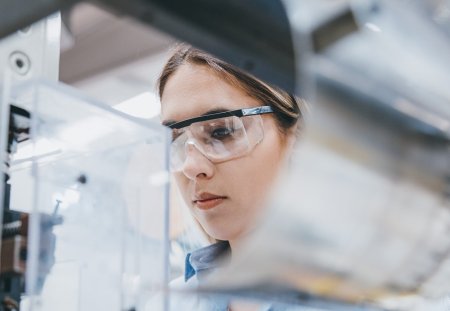 Professional young industrial factory woman employee working with machine parts putting, checking and testing industrial equipments cables in large Electric electronics wire and cable manufacturing plant factory warehouse