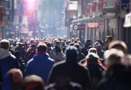 A crowd of people on a bright winter day on an urban high street in Europe, anonymous faces