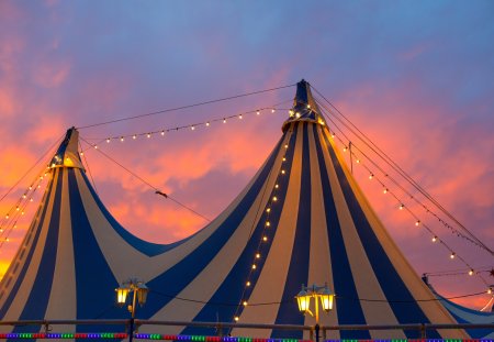 Circus tent in a dramatic sunset sky colorful orange blue with lights