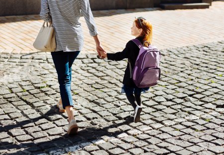 Crossing the street. Amazing little female keeping rucksack on her back while going to school