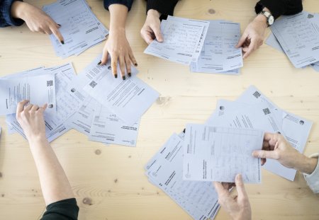 Freiwillige Mitarbeiter helfen beim Auslesen der Abstimmungsunterlagen zur Regierungs- und Kantonsratswahlen 2023 im Schulhaus Aemtler, aufgenommen am Sonntag, 12. Februar 2023, in Zuerich. (KEYSTONE/Ennio Leanza)