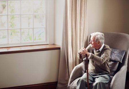 Shot of a senior man looking thoughtfully out of a window at home