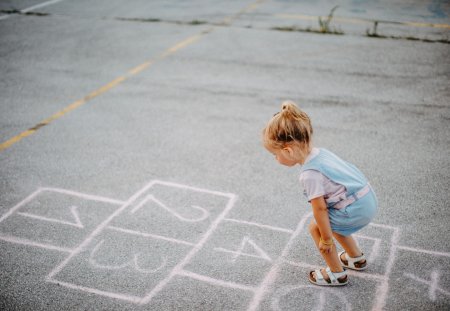 Girl playing hopscotch in public park