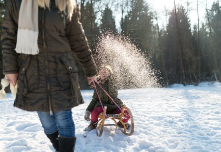 Mother pulls daughter on sledge