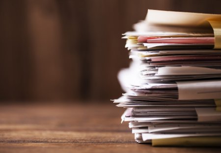 Large stack of files, paperwork on office desk with copyspace.  Overworked concept.
