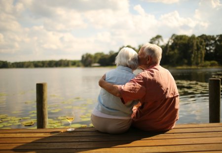 Rear view of romantic senior man kissing woman on wooden pier