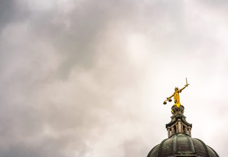 Storm clouds gathering above and around the statue of Lady Justice on the top of the main dome of the Royal Courts of Justice, known as Old Bailey after the street name in the City of London.